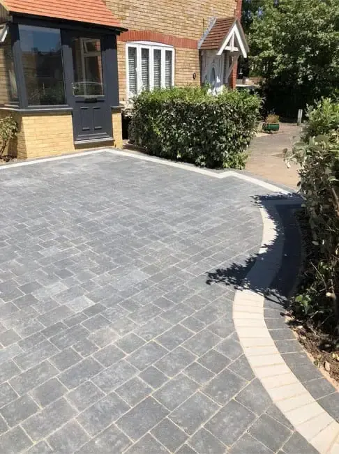 Silver-grey block paved driveway with a buff soldier course curving towards a house