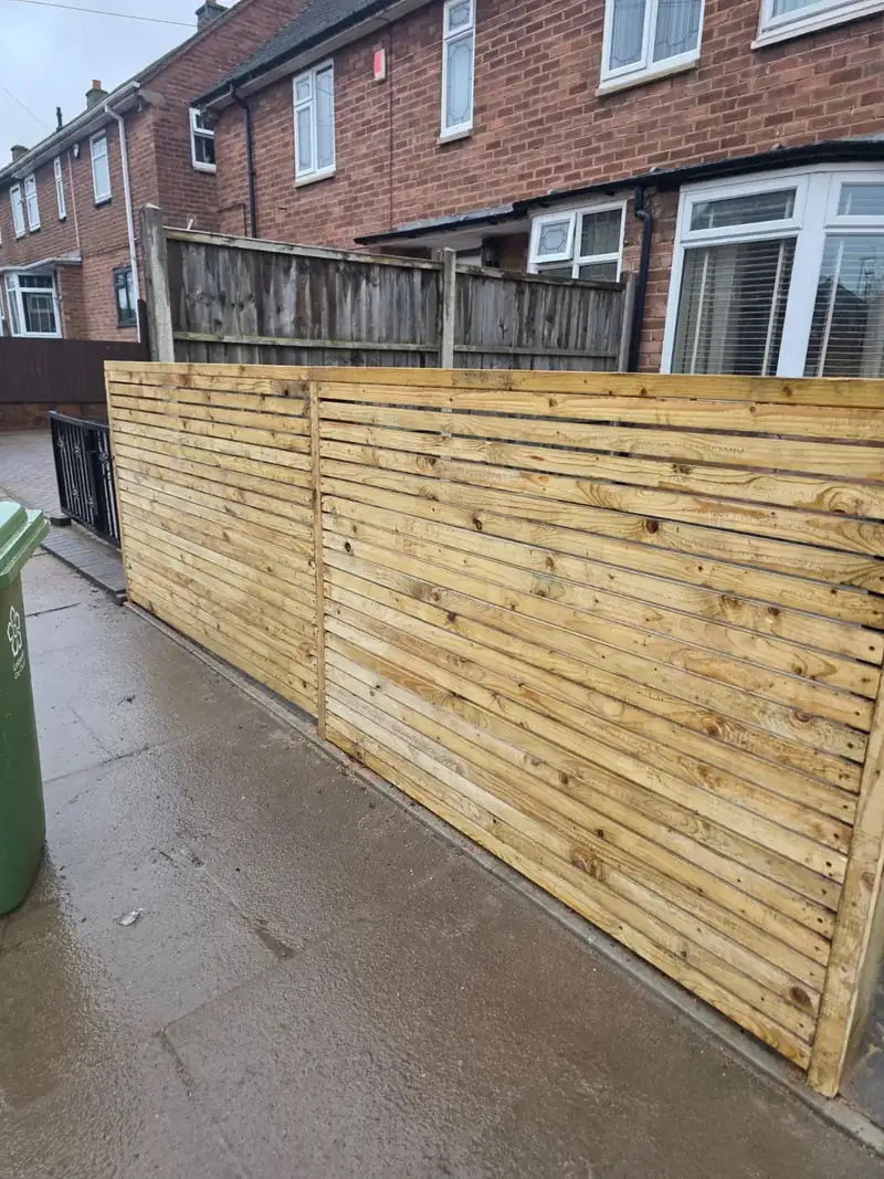 Grey paved pathway running along a timber fence at the side of a house