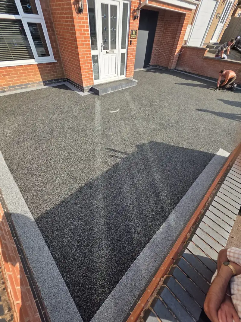 Freshly laid black tarmac driveway with a pale block paved border
